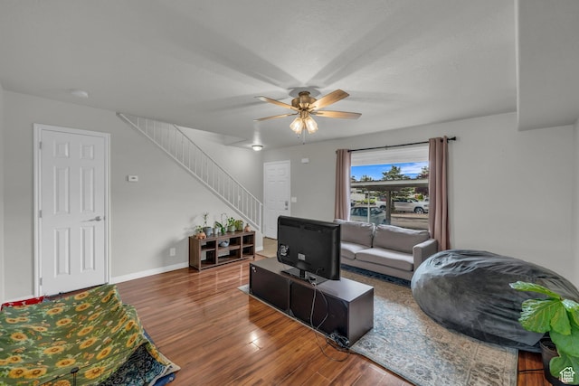 living area with wood finished floors, stairs, ceiling fan, and baseboards