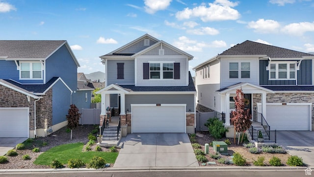 craftsman inspired home featuring driveway, an attached garage, stone siding, and fence