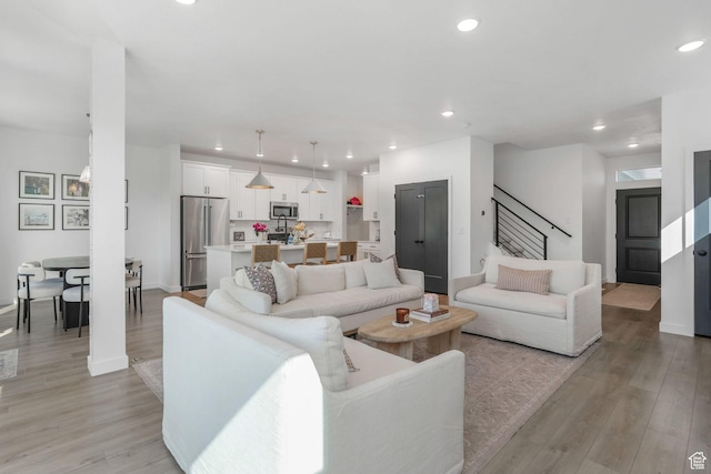 living area with recessed lighting, light wood-style floors, stairway, and baseboards
