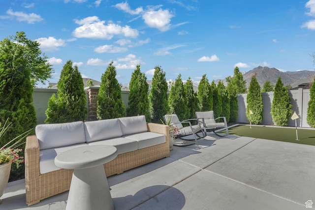 view of patio / terrace featuring a putting area, outdoor lounge area, a mountain view, and a fenced backyard