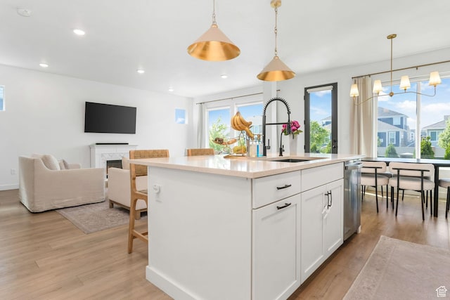 kitchen featuring a sink, stainless steel dishwasher, light wood-style flooring, white cabinets, and recessed lighting