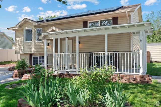 back of property with covered porch and solar panels