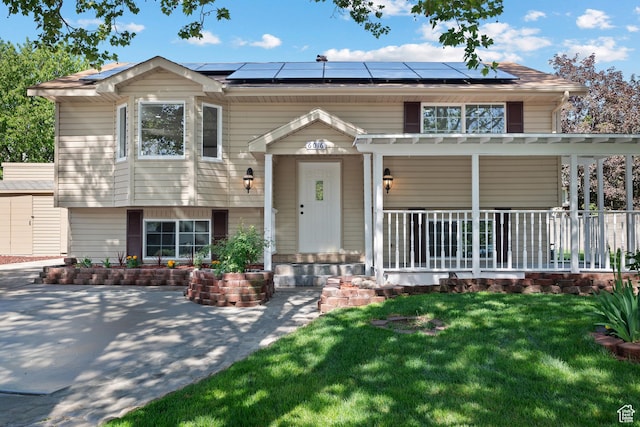 view of front of property with a porch, roof mounted solar panels, and a front lawn