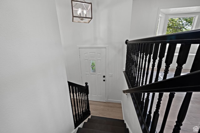 stairway featuring baseboards, wood finished floors, and a chandelier