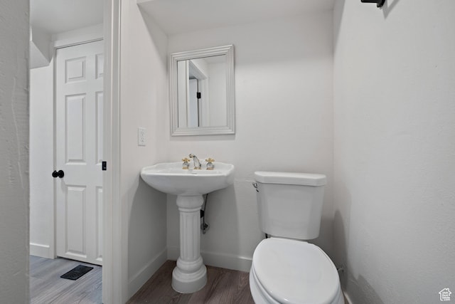half bath featuring toilet, wood finished floors, and baseboards