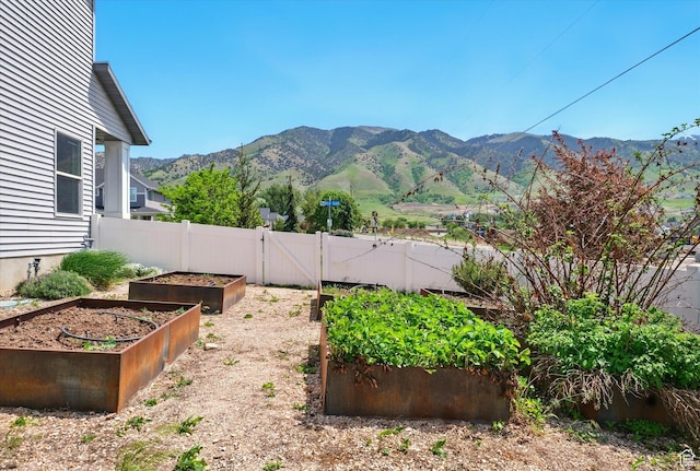 view of yard with a garden, a mountain view, fence, and a gate