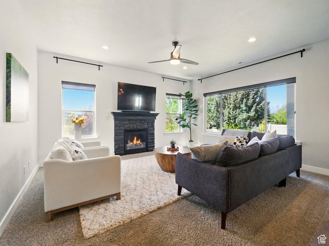 carpeted living room featuring baseboards, recessed lighting, a stone fireplace, and ceiling fan