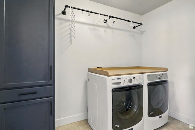 laundry area featuring washing machine and dryer, baseboards, and light tile patterned floors
