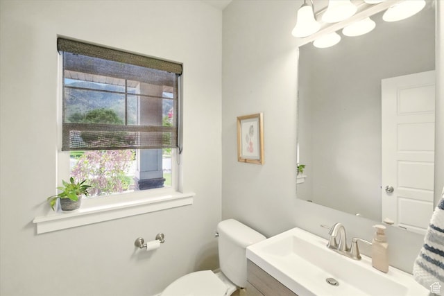 bathroom featuring toilet, vanity, and a chandelier
