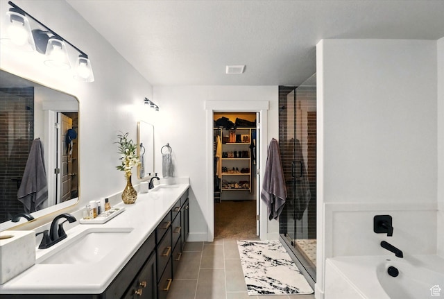 full bathroom featuring tile patterned flooring, a stall shower, a walk in closet, double vanity, and a bathtub