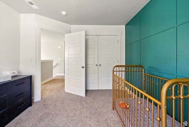 carpeted bedroom with a closet and a crib