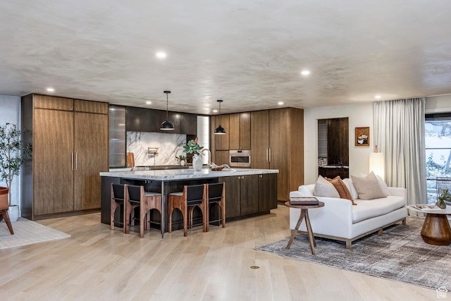 4279 S Lares Cir, Salt Lake City, UT 84124 - kitchen with stainless steel oven, recessed lighting, light wood-style floors, a large island, and a kitchen bar