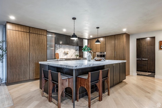 4279 S Lares Cir, Salt Lake City, UT 84124 - kitchen with stainless steel oven, light wood-type flooring, a spacious island, recessed lighting, and light stone counters