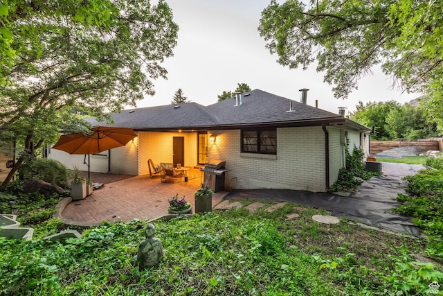 4279 S Lares Cir, Salt Lake City, UT 84124 - back of property featuring a patio, brick siding, and a shingled roof