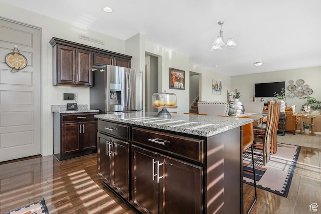 9559 S Lea Heather Way, West Jordan, UT 84081 - kitchen with stainless steel fridge with ice dispenser, light stone counters, dark brown cabinets, dark wood-style flooring, and decorative light fixtures