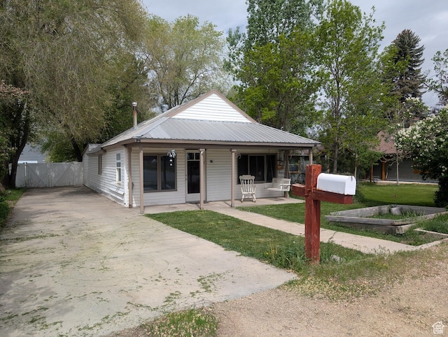 view of front of property featuring a gate, concrete driveway, and metal roof