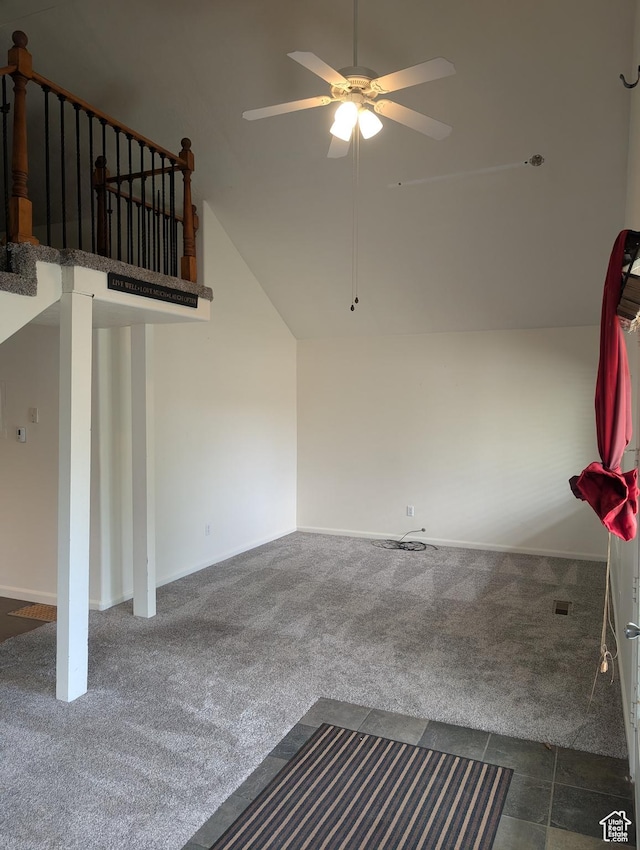 unfurnished living room featuring dark colored carpet, ceiling fan, lofted ceiling, and baseboards