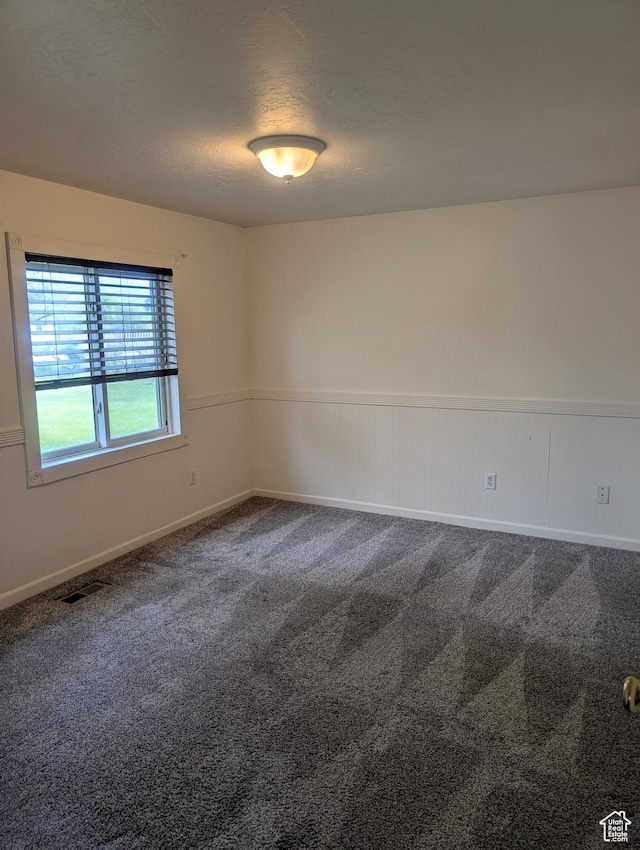 spare room with carpet floors, a textured ceiling, and baseboards