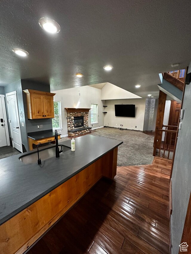 kitchen featuring dark wood-style floors, dark countertops, open floor plan, a fireplace, and a textured ceiling