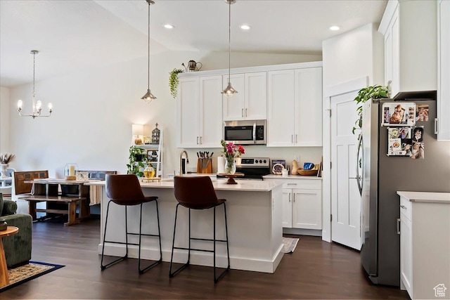 1008 N Vista Loop, Morgan, UT 84050 - kitchen featuring appliances with stainless steel finishes, vaulted ceiling, dark wood-type flooring, a breakfast bar area, and white cabinetry