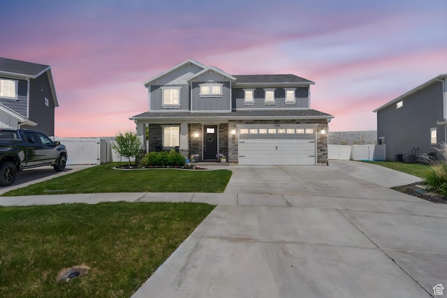 view of front of house featuring a gate, concrete driveway, a garage, stone siding, and board and batten siding