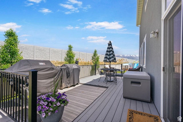 wooden terrace featuring outdoor dining area, a water view, and area for grilling