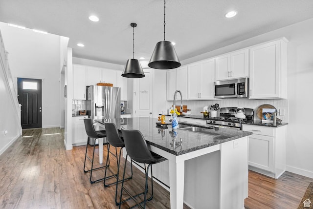 kitchen featuring stainless steel appliances, tasteful backsplash, recessed lighting, light wood-style floors, and baseboards