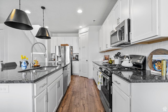 kitchen with appliances with stainless steel finishes, a sink, white cabinetry, a kitchen island with sink, and recessed lighting