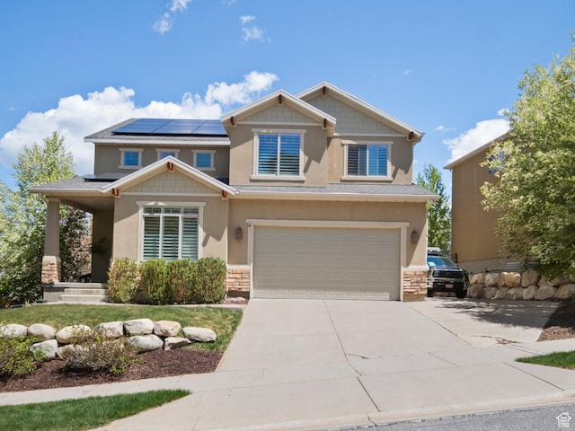 craftsman-style home with stone siding, roof mounted solar panels, a garage, and stucco siding