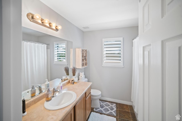 full bath featuring toilet, vanity, and baseboards