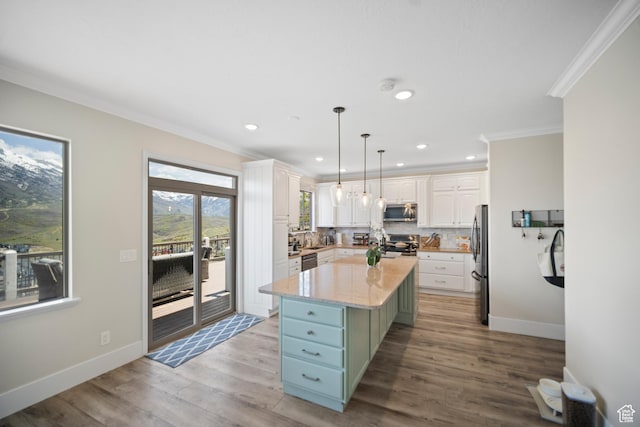 kitchen with appliances with stainless steel finishes, white cabinetry, crown molding, a center island, and decorative backsplash
