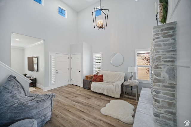 living area featuring wood finished floors, a high ceiling, plenty of natural light, a chandelier, and baseboards