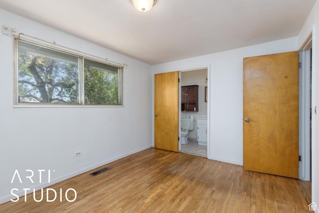 unfurnished bedroom featuring light wood-type flooring, baseboards, and ensuite bathroom