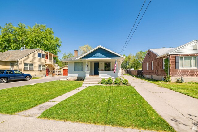 141 W 400 N, Logan, UT 84321 - bungalow featuring a porch, a chimney, a front yard, and driveway