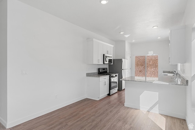 7308 Bald Eagle Way N, Eagle Mountain, UT 84005 - kitchen with stainless steel appliances, white cabinets, a sink, wood finished floors, and recessed lighting