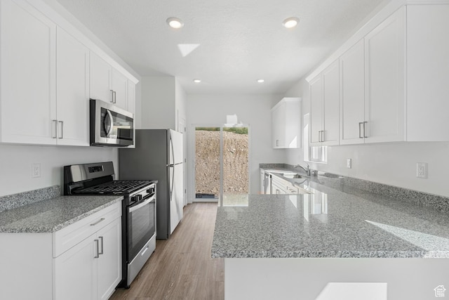 7308 Bald Eagle Way N, Eagle Mountain, UT 84005 - kitchen featuring stainless steel appliances, light stone counters, white cabinetry, a peninsula, and a sink