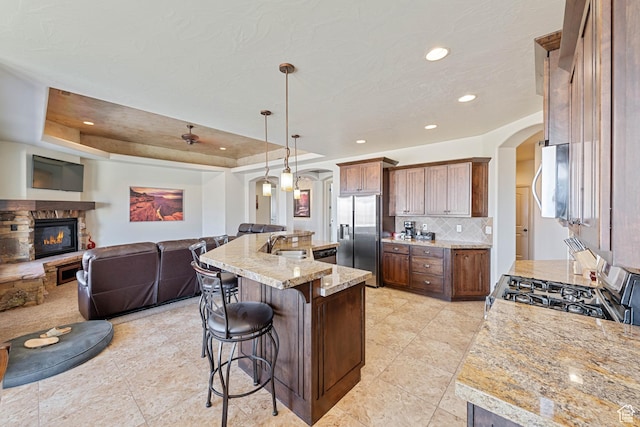 kitchen with arched walkways, appliances with stainless steel finishes, a fireplace, open floor plan, and recessed lighting