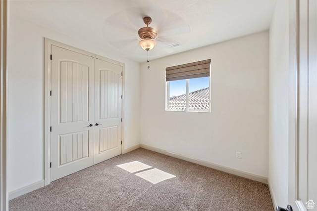 unfurnished bedroom featuring light colored carpet, a closet, baseboards, and a ceiling fan
