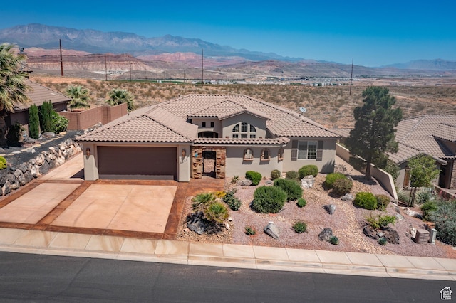 mediterranean / spanish home with a mountain view, stucco siding, an attached garage, and a tile roof
