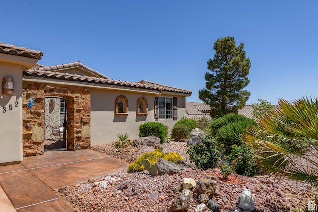 view of front facade with stone siding, a tiled roof, and stucco siding