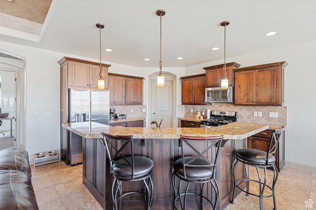 kitchen featuring appliances with stainless steel finishes, arched walkways, tasteful backsplash, a breakfast bar area, and recessed lighting