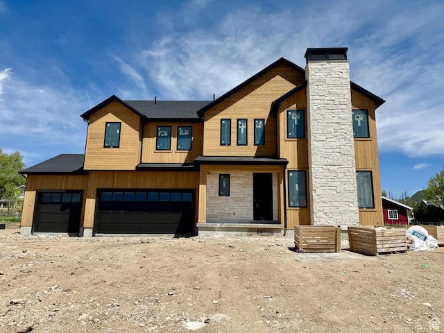 modern home featuring a garage, stone siding, and a chimney