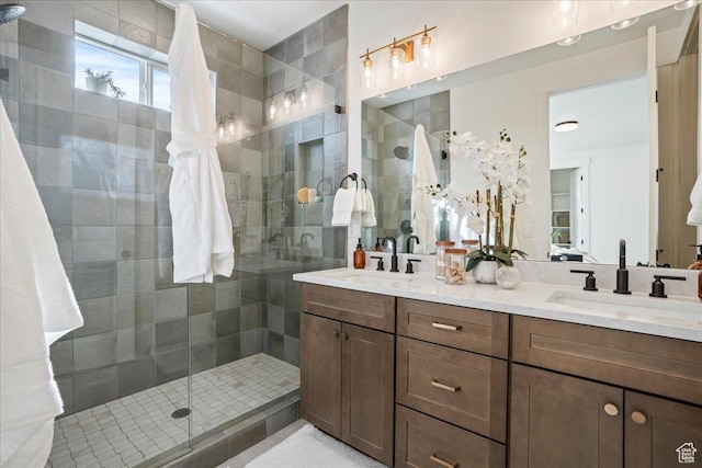 full bath with a tile shower and double vanity