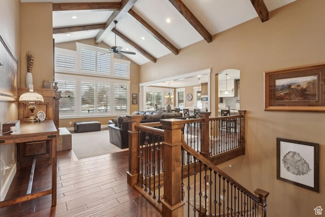 stairway featuring ceiling fan, beam ceiling, wood finished floors, arched walkways, and high vaulted ceiling