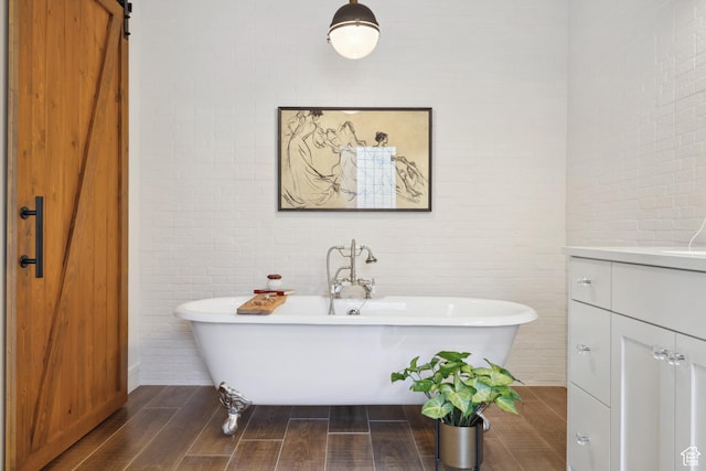bathroom featuring a soaking tub, vanity, and wood finished floors