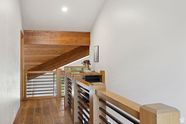 stairway featuring vaulted ceiling, wood finished floors, recessed lighting, and baseboards