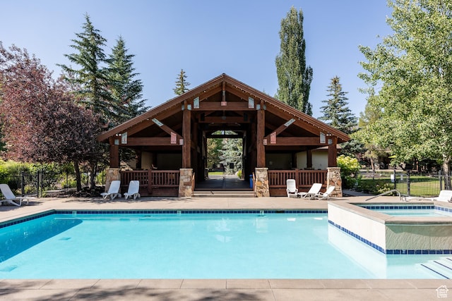 community pool featuring a hot tub, fence, a gazebo, and a patio