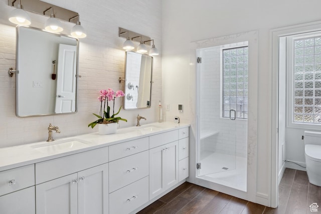full bath with toilet, wood finished floors, a shower stall, and double vanity