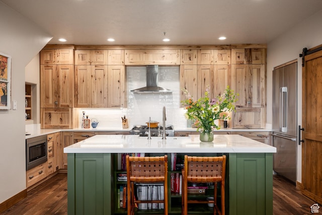 kitchen with wall chimney exhaust hood, appliances with stainless steel finishes, a barn door, light countertops, and backsplash