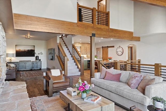 living room featuring hardwood / wood-style flooring, stairway, arched walkways, recessed lighting, and a high ceiling